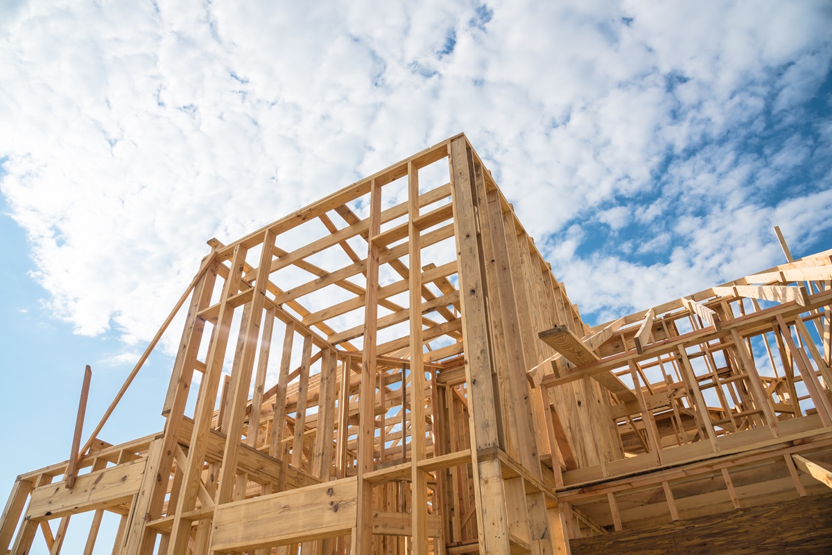 Close-up new stick built home under construction under blue sky in Humble, Texas, US. Framing structure/wood frame of wooden houses/home. House construction and real estate concept background.